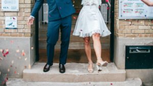 Couple sortant de la mairie le jour de leur mariage civil, confettis colorés, robe courte et costume bleu
